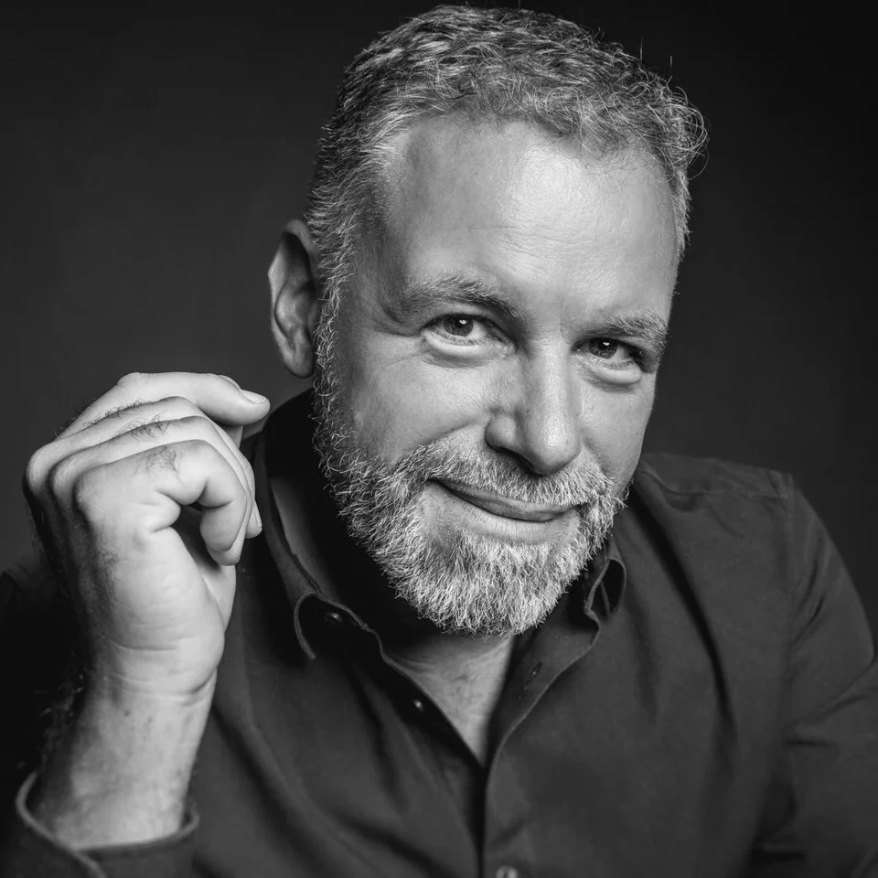Stéphane Rohmer, portrait en noir et blanc, la main près du visage.